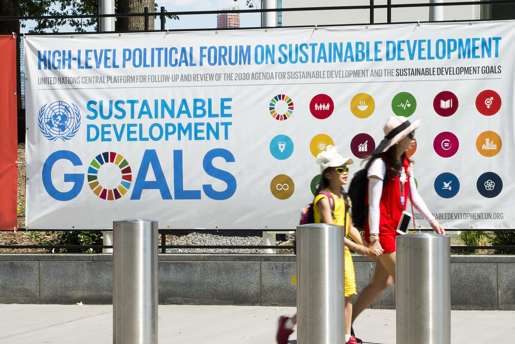 Poster for HLPF, 2 schoolgirls walk by in front of it