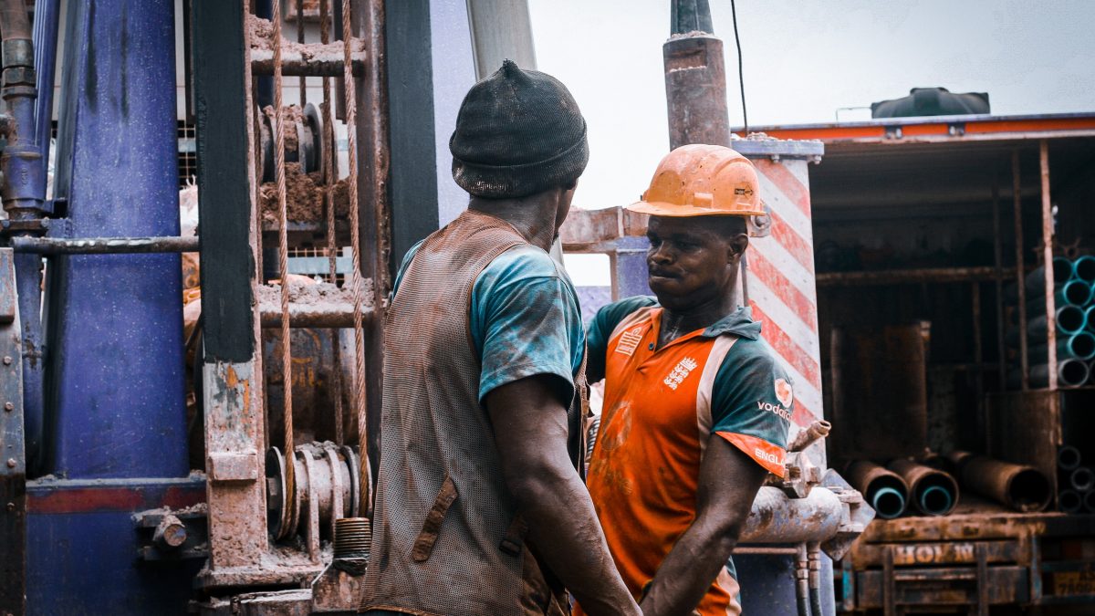 workers standing beside drilling machine